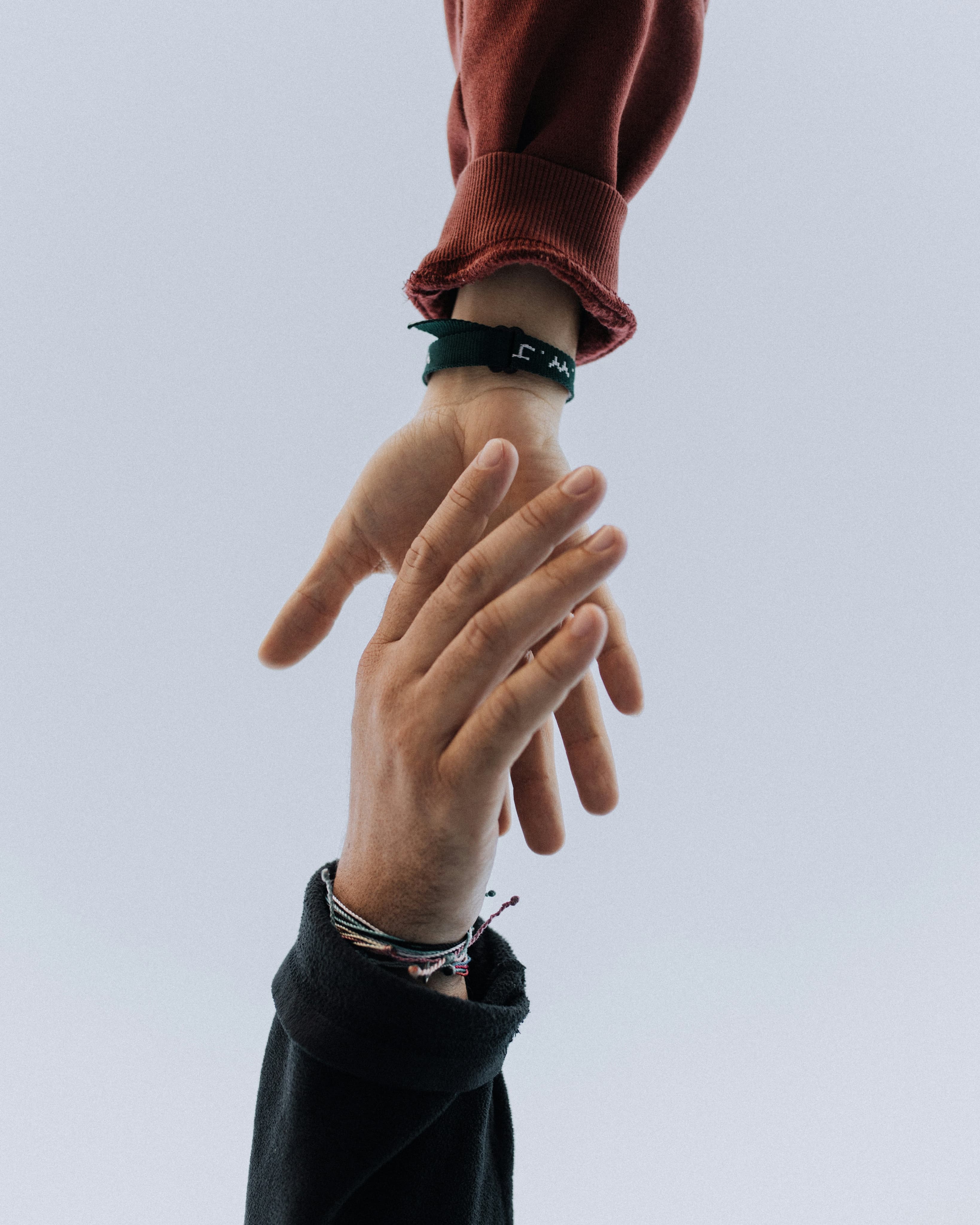 One person reaching down to help pull up another